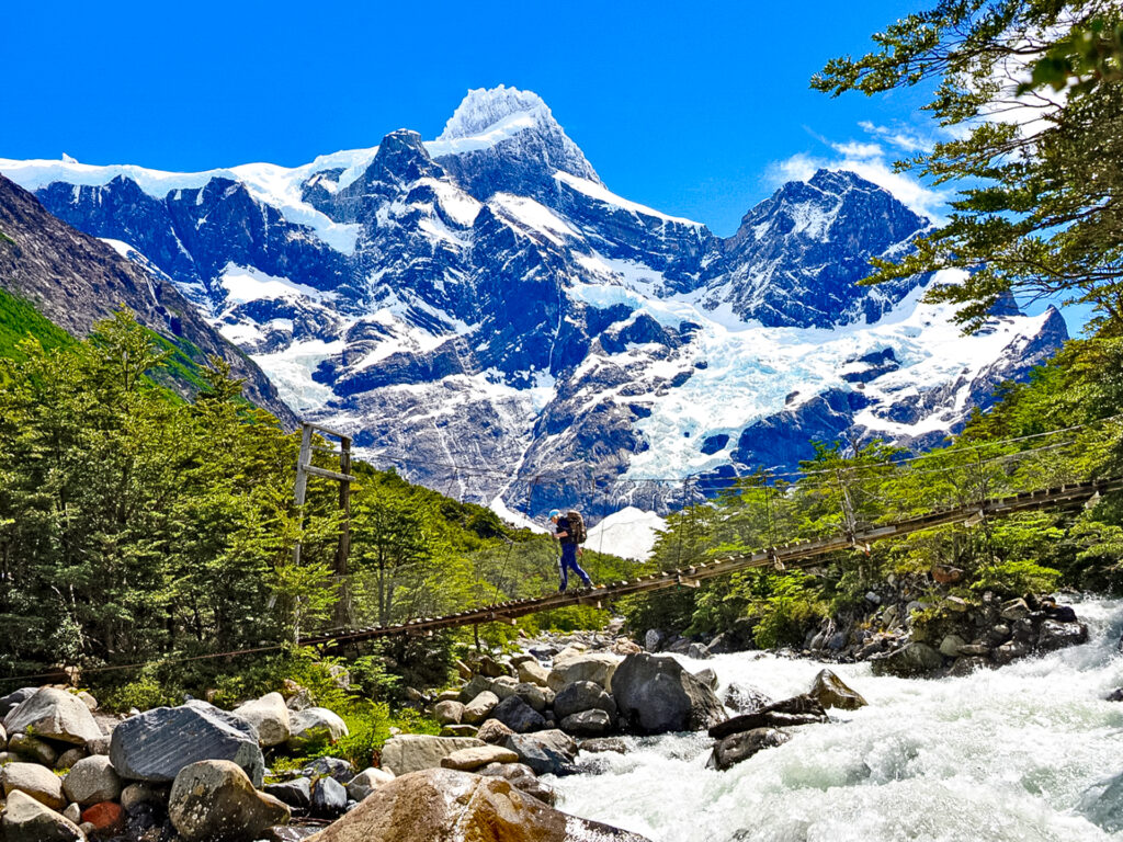 Fluss mit Brücke und Wanderer, mit Andengipfel im Hintergrund