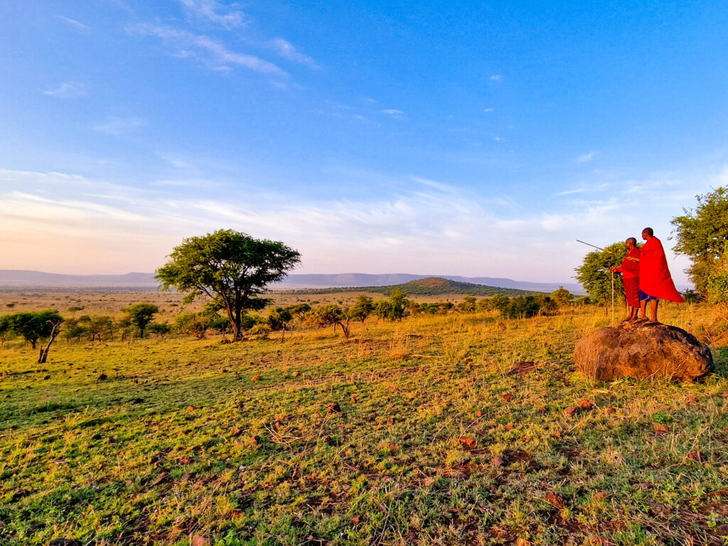 2 einheimische Guides stehen auf einem Stein in der Savanne
